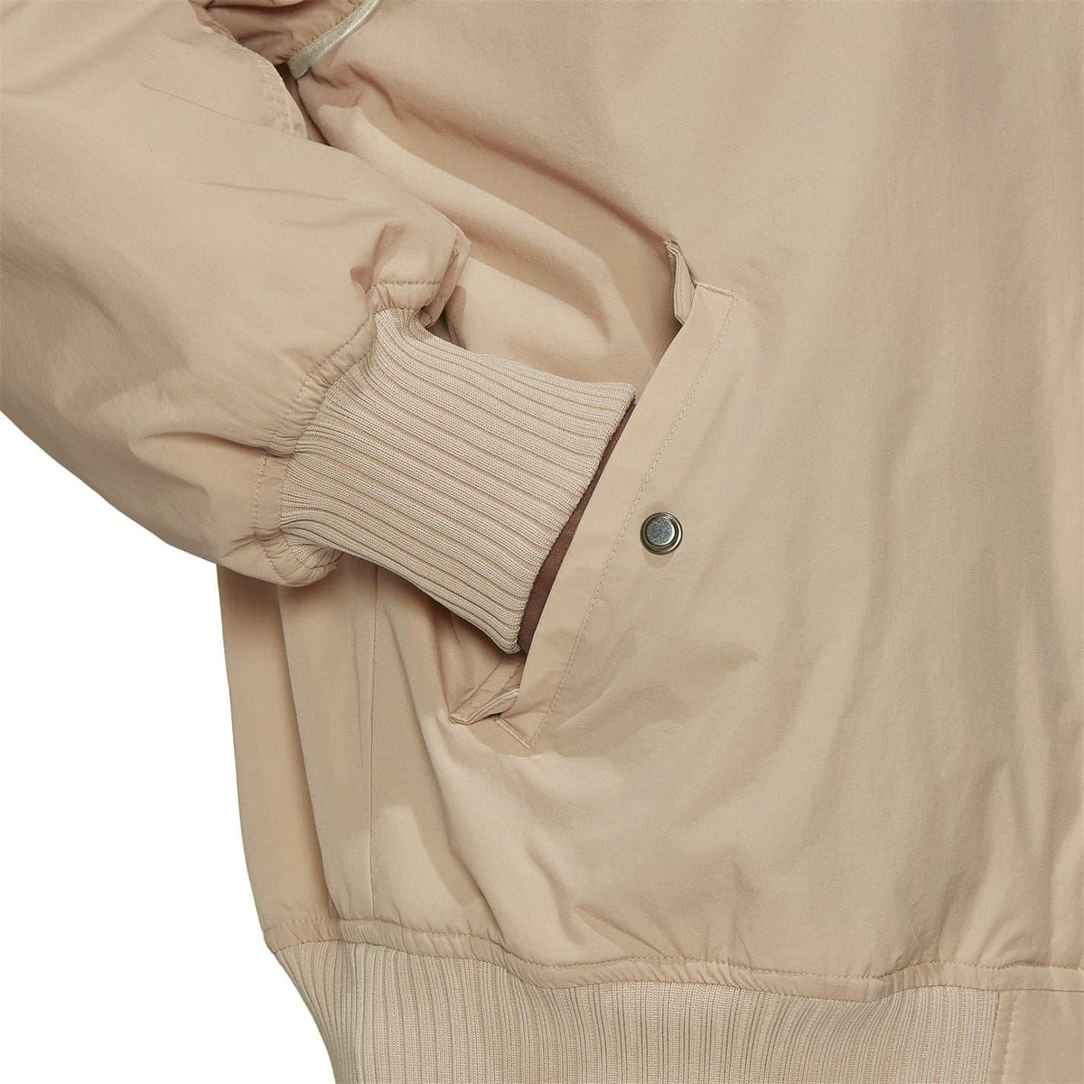 Beige bomber jacket sleeve close-up with ribbed cuff and zip pocket detail.