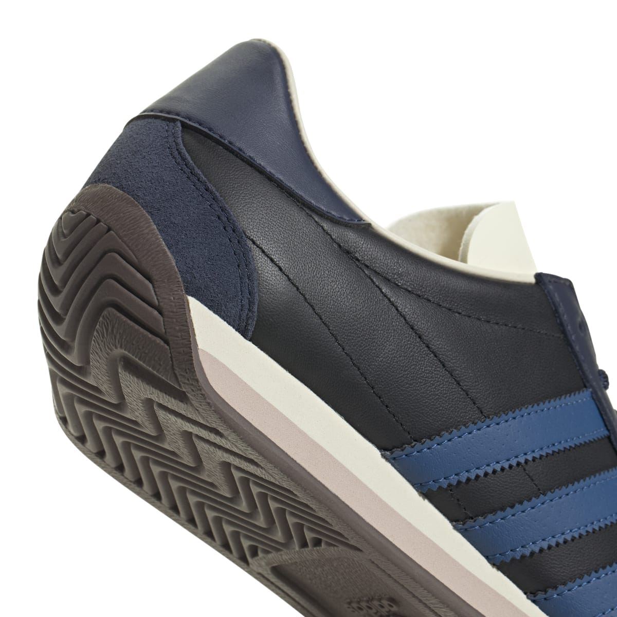 Close-up of heel and side seams on navy/black trainer with blue stripe panel and tread sole