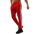 Red adidas track pants with white side stripes and elastic ankle cuffs