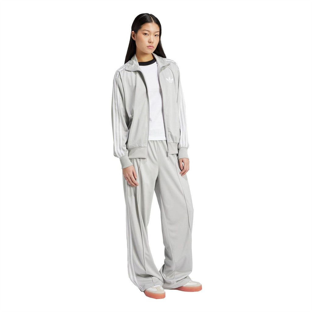Grey adidas Originals track pants on model, relaxed wide leg with elastic cuffs