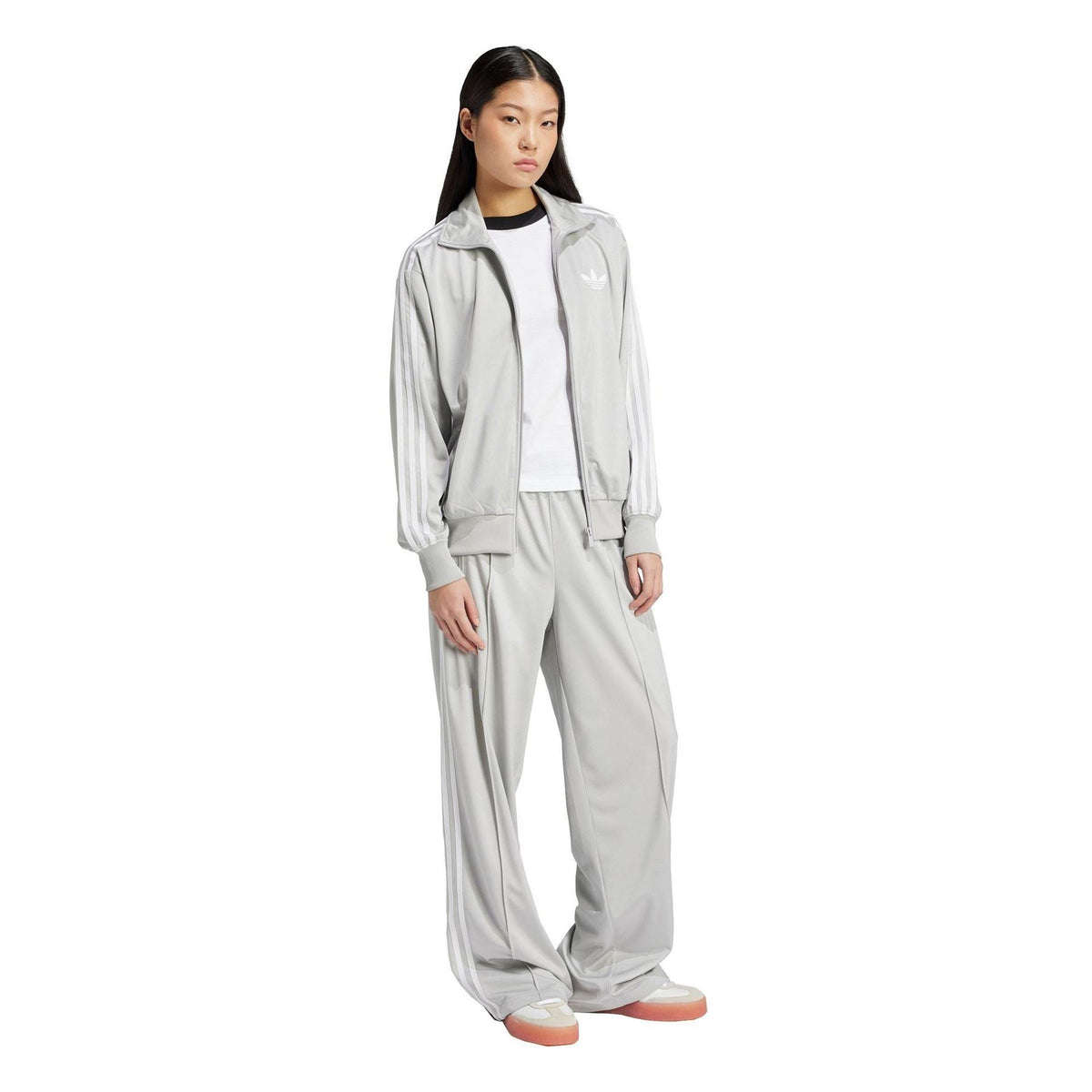 Grey adidas Originals track pants on model, relaxed wide leg with elastic cuffs