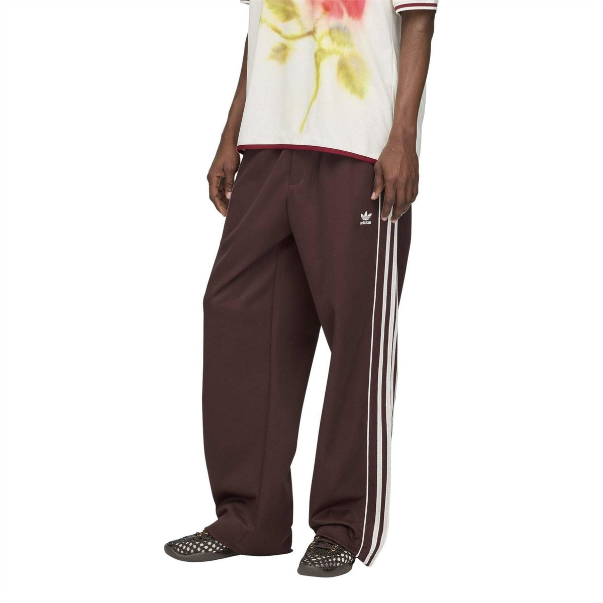 Dark maroon track pants with white triple side stripes and relaxed straight-leg fit.