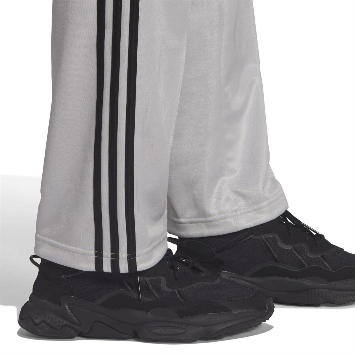Light gray sweatpants with black side stripes and elastic cuffs over sneakers