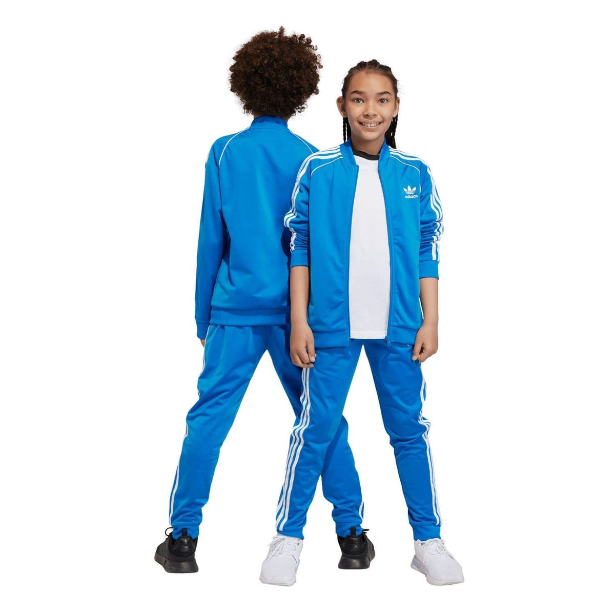 Blue kids track pants with white side stripes, worn with sneakers