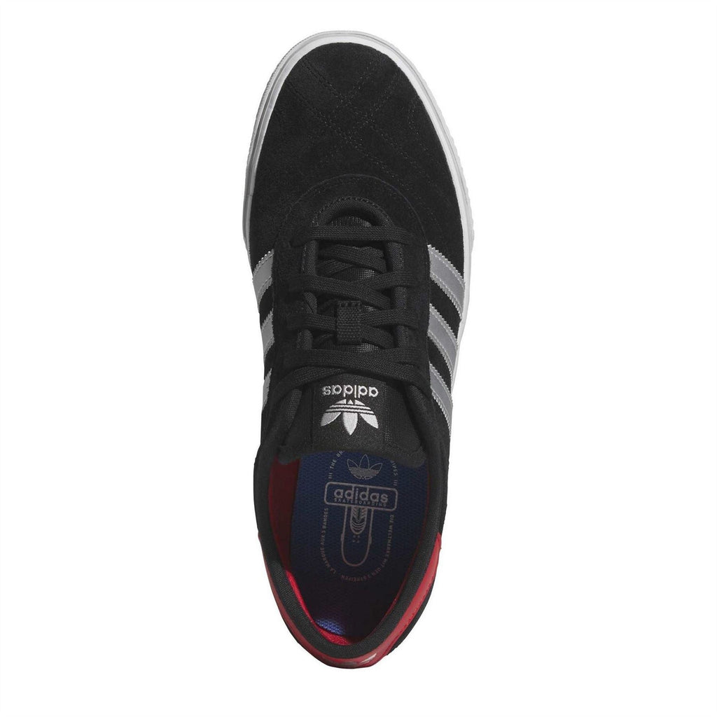 Black suede sneaker top view with lace-up closure and white side stripes, red lining.