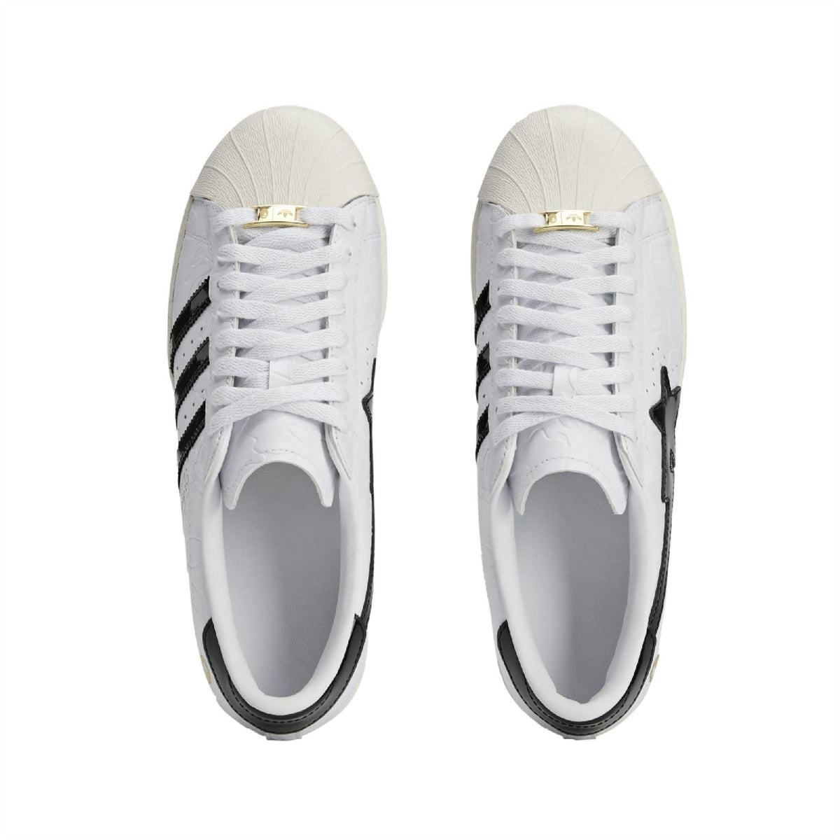 Pair of white sneakers with white laces, black side stripes, and gold lace tag