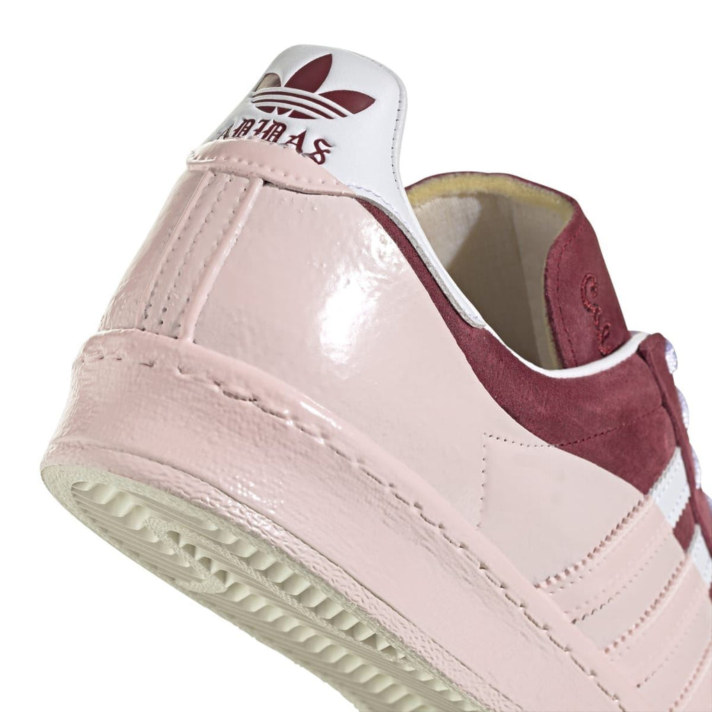 Close-up heel of off-white low-top sneaker with burgundy inner lining and side stitching