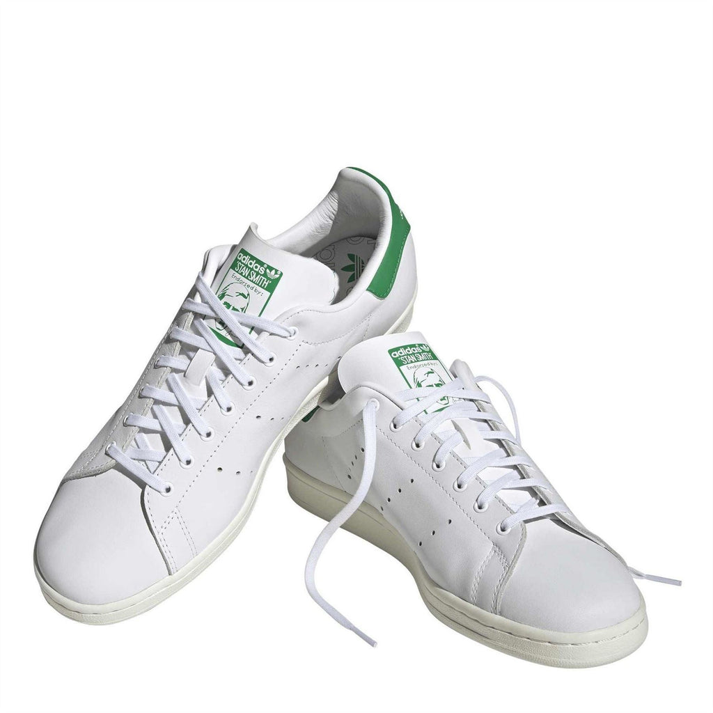 White lace-up sneakers with green collar accents and adidas logo on side