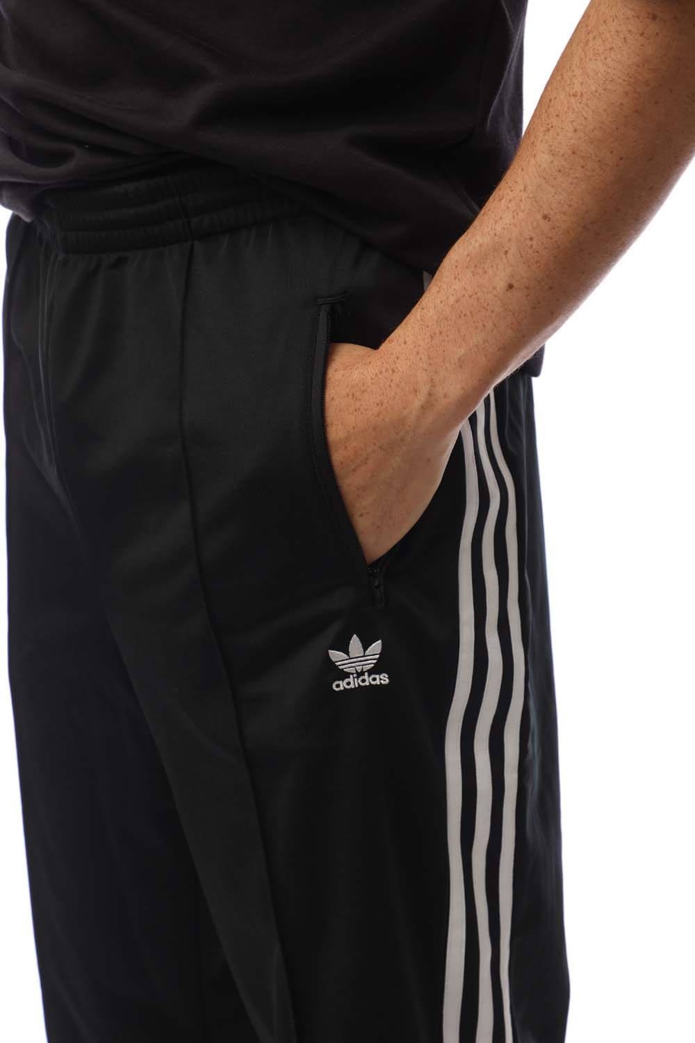 Black track pants close-up with adidas logo and white side stripes