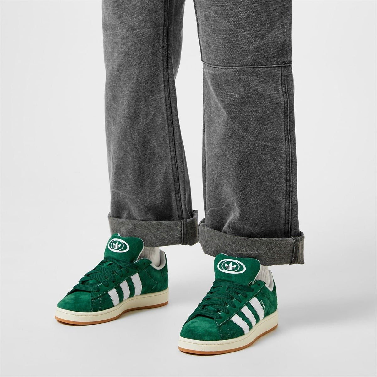 Dark green trainers worn with grey cuffed trousers; white adidas stripes and laces