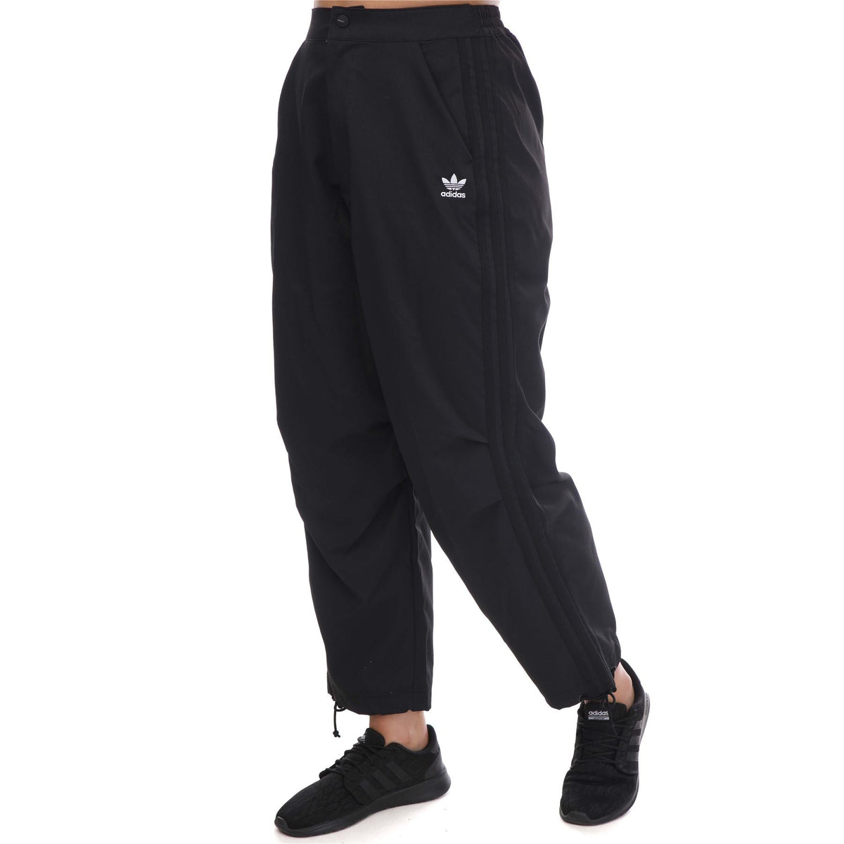 adidas Originals Adicolor Classic woven track pants with elastic waistband and side pockets, black with white stripes.