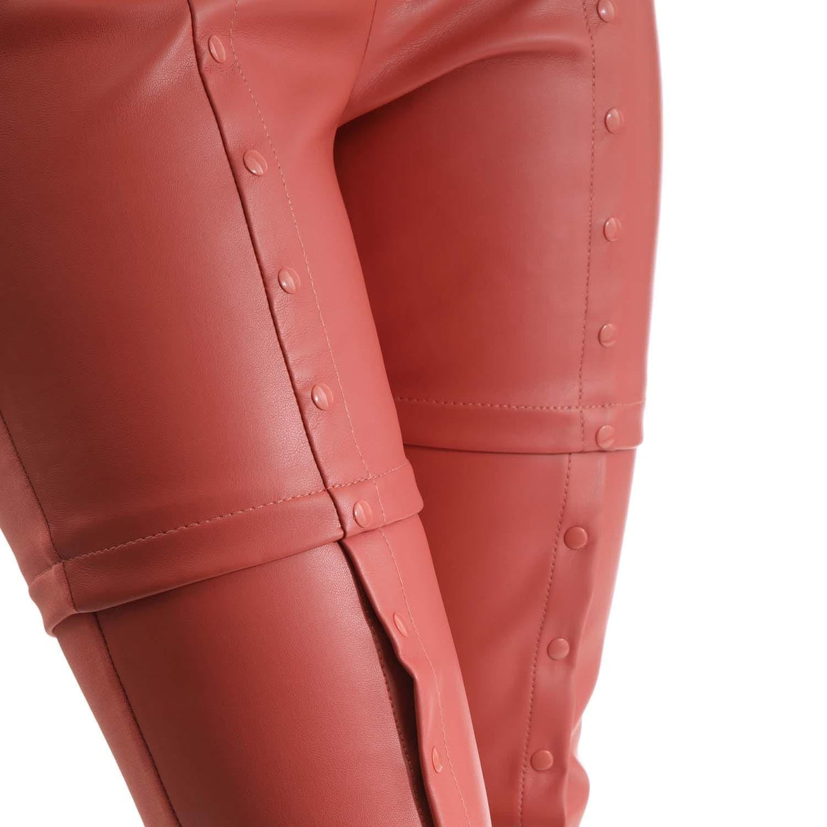 Lower leg detail of red snap-button pants with stitched panel and snap fasteners