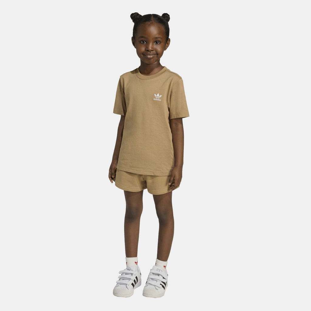 Tan adidas juniors T-shirt and shorts set on model, front view; short sleeves and sneakers