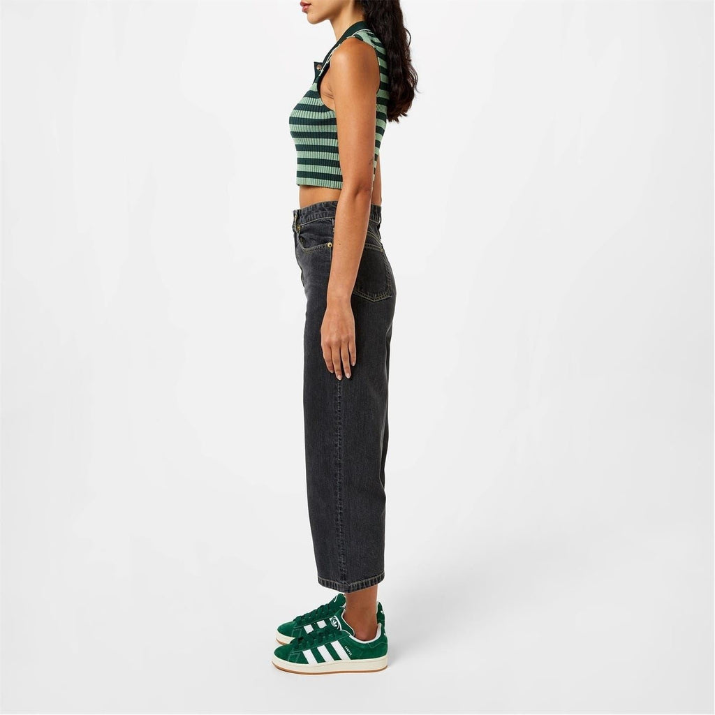 Green adidas sneakers with white stripes and gum sole, worn with dark jeans