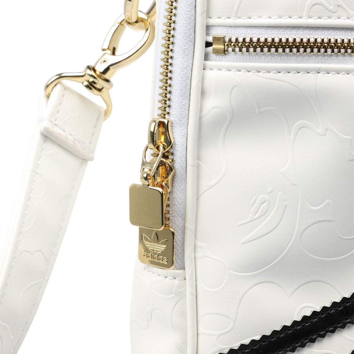 White adidas Originals BAPE bag close-up of gold zippers, hooks, and embossed texture