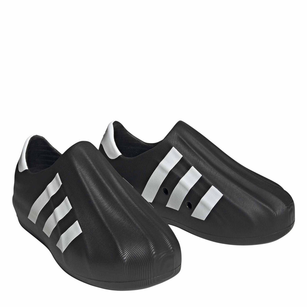 Pair of black slip-on sneakers with white adidas-style stripes on textured uppers