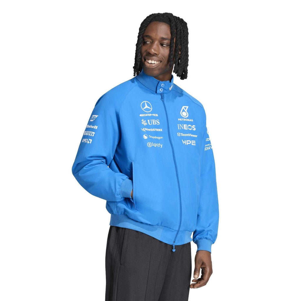 Blue zip-up jacket with stand collar and team logos across chest and sleeves.