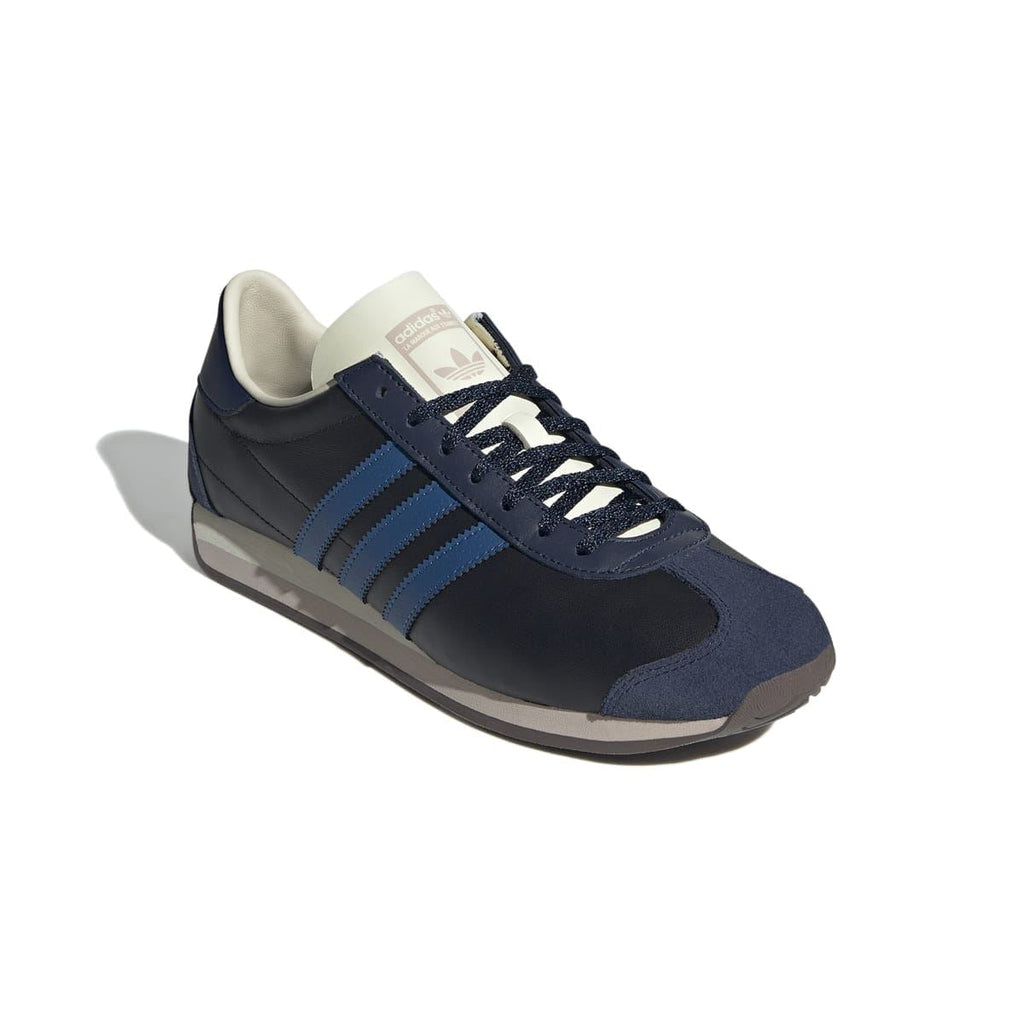Side view of navy/black Country OG trainer with blue stripes, cream lining, and laces