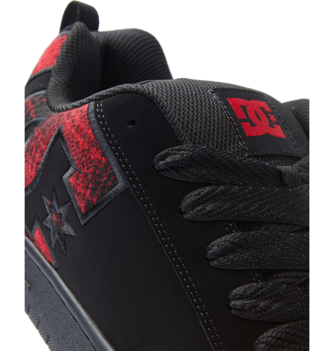 Close-up of black sneaker with red heel patch and black lace-up panel