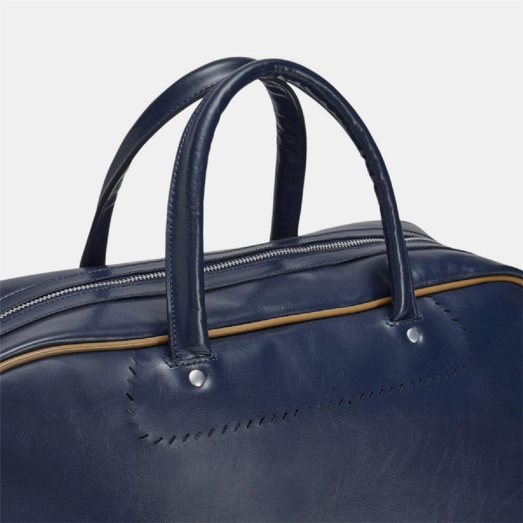 Navy duffel bag close-up of top handles and gold-trimmed zipper edge