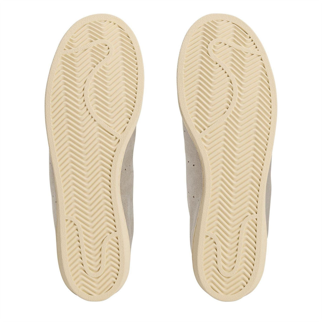 Cream rubber sneaker soles with textured herringbone tread pattern.