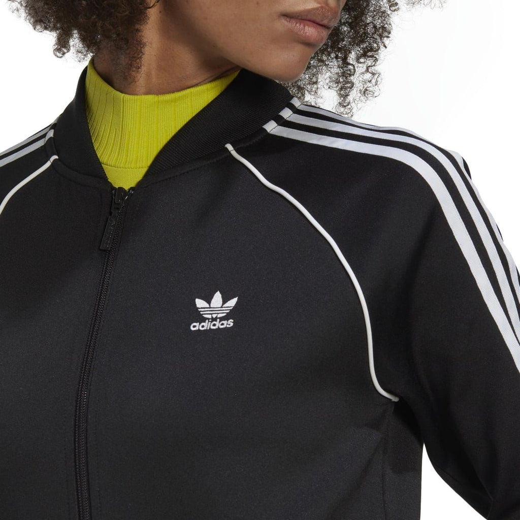 Black track top close-up: adidas logo, white piping stripes, stand collar zip
