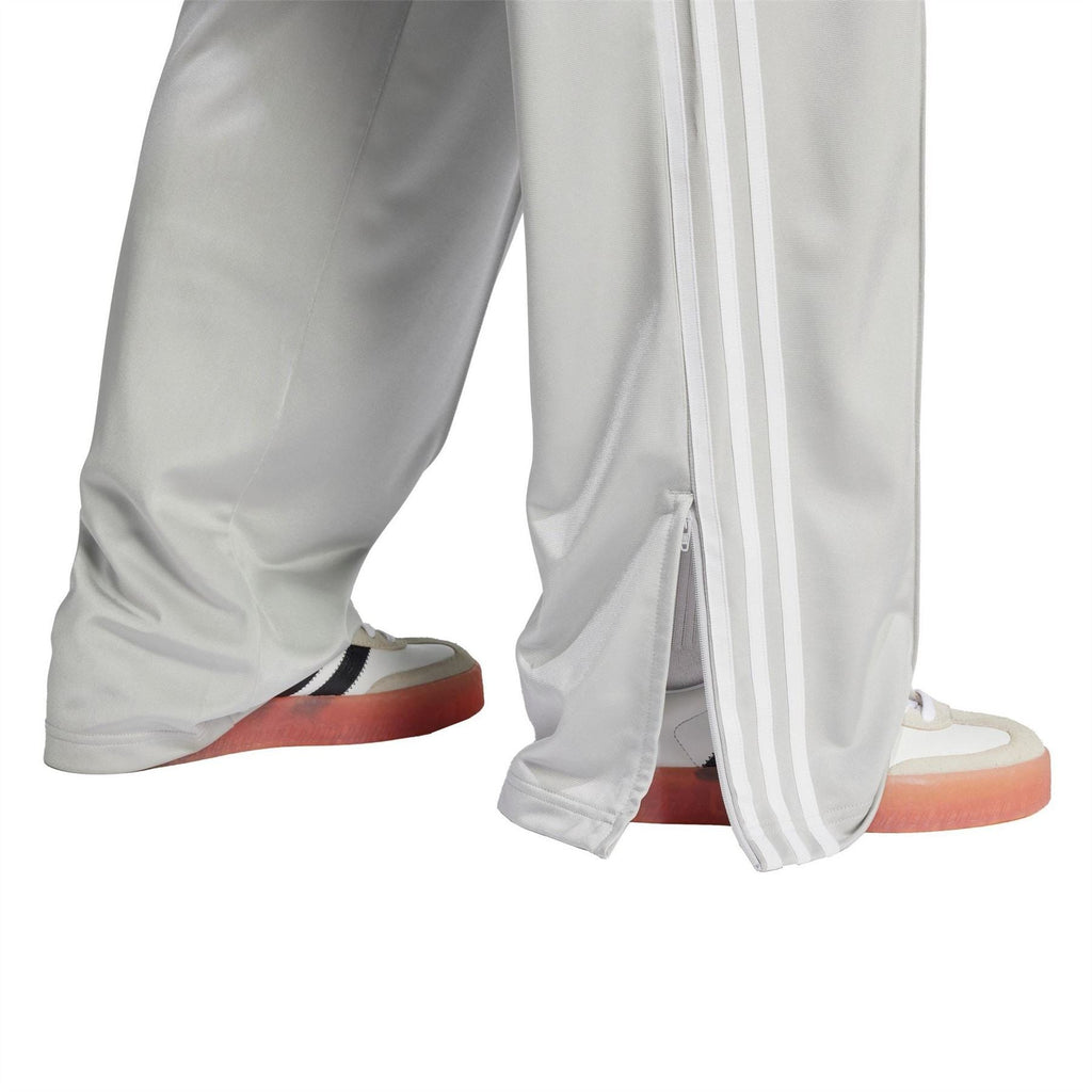 Grey adidas Originals track pants with three white side stripes and front zip pocket