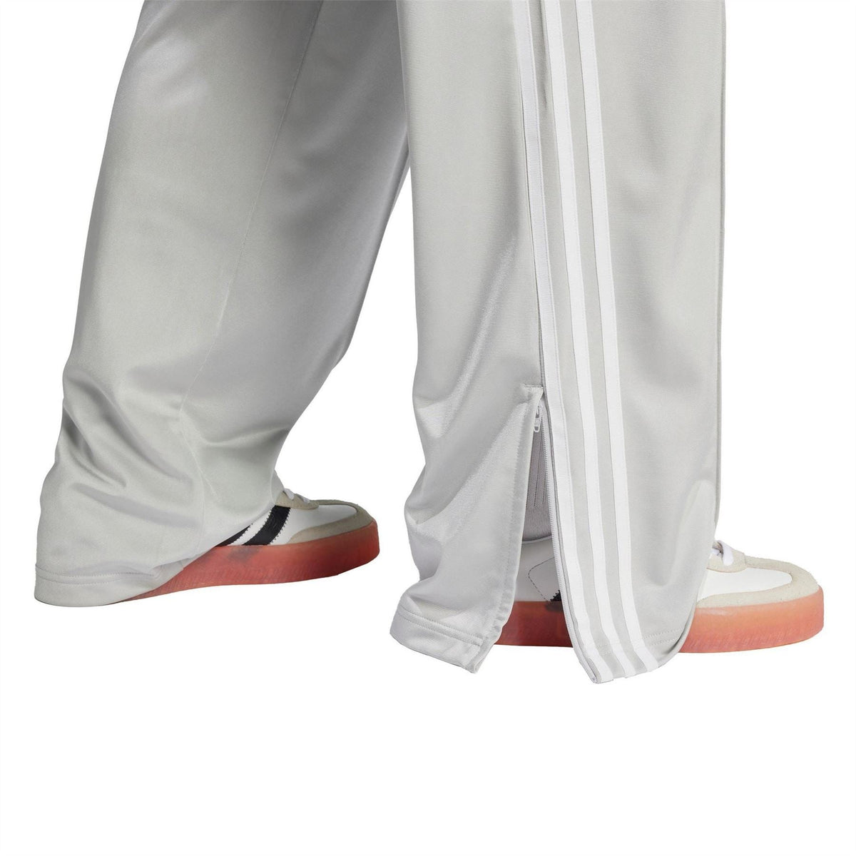 Grey adidas Originals track pants with three white side stripes and front zip pocket