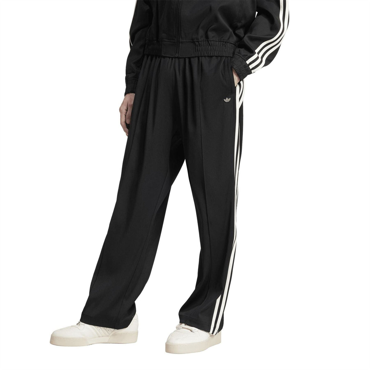 Black baggy track pants with side white stripes and ankle-length tapered leg