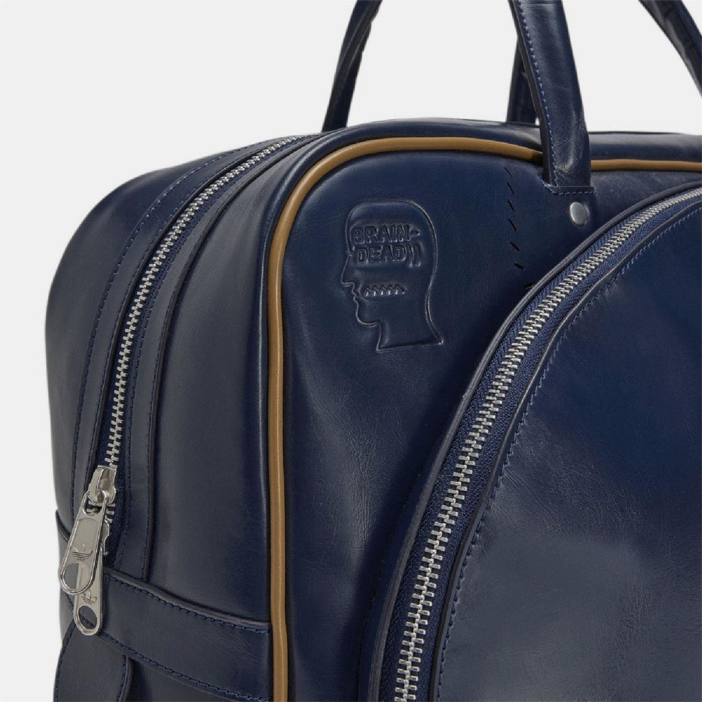 Navy duffel bag side close-up with embossed profile patch and silver zipper