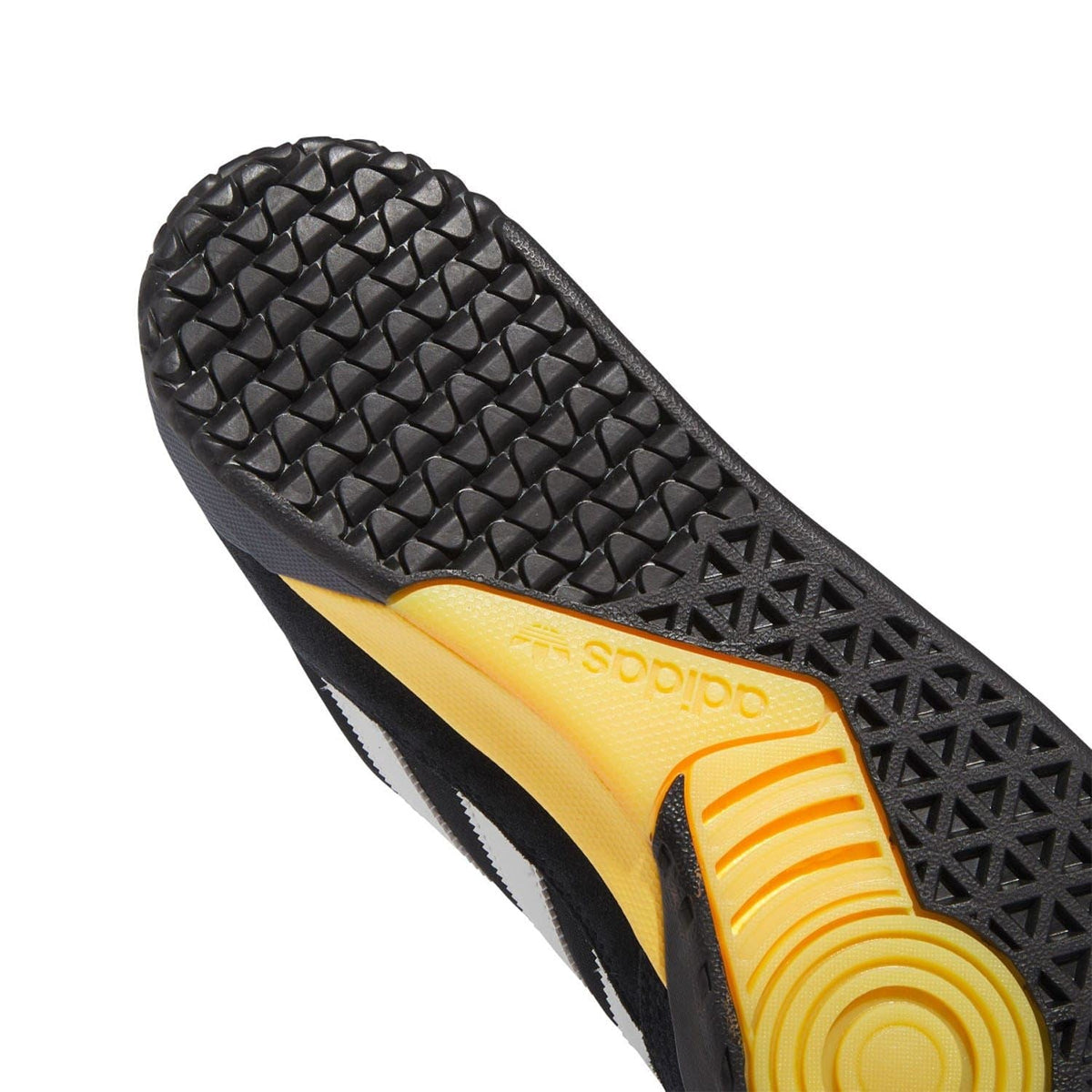 Close-up of black textured outsole with adidas branding and yellow insert detail