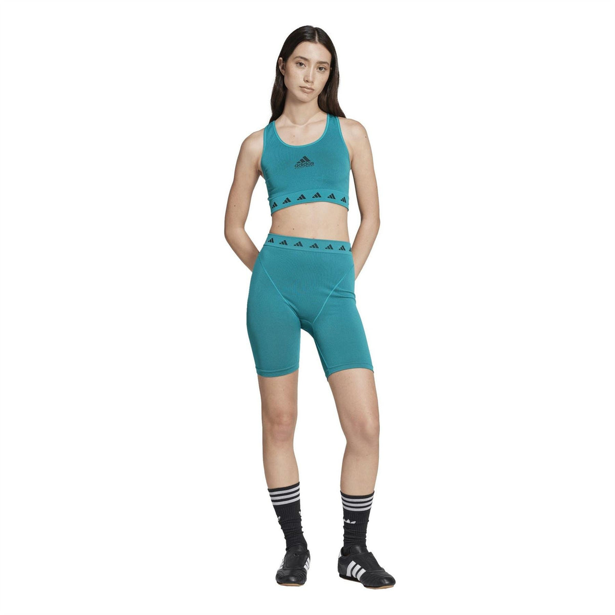 Teal adidas Originals cropped sports top with patterned hem band; paired with teal biker shorts