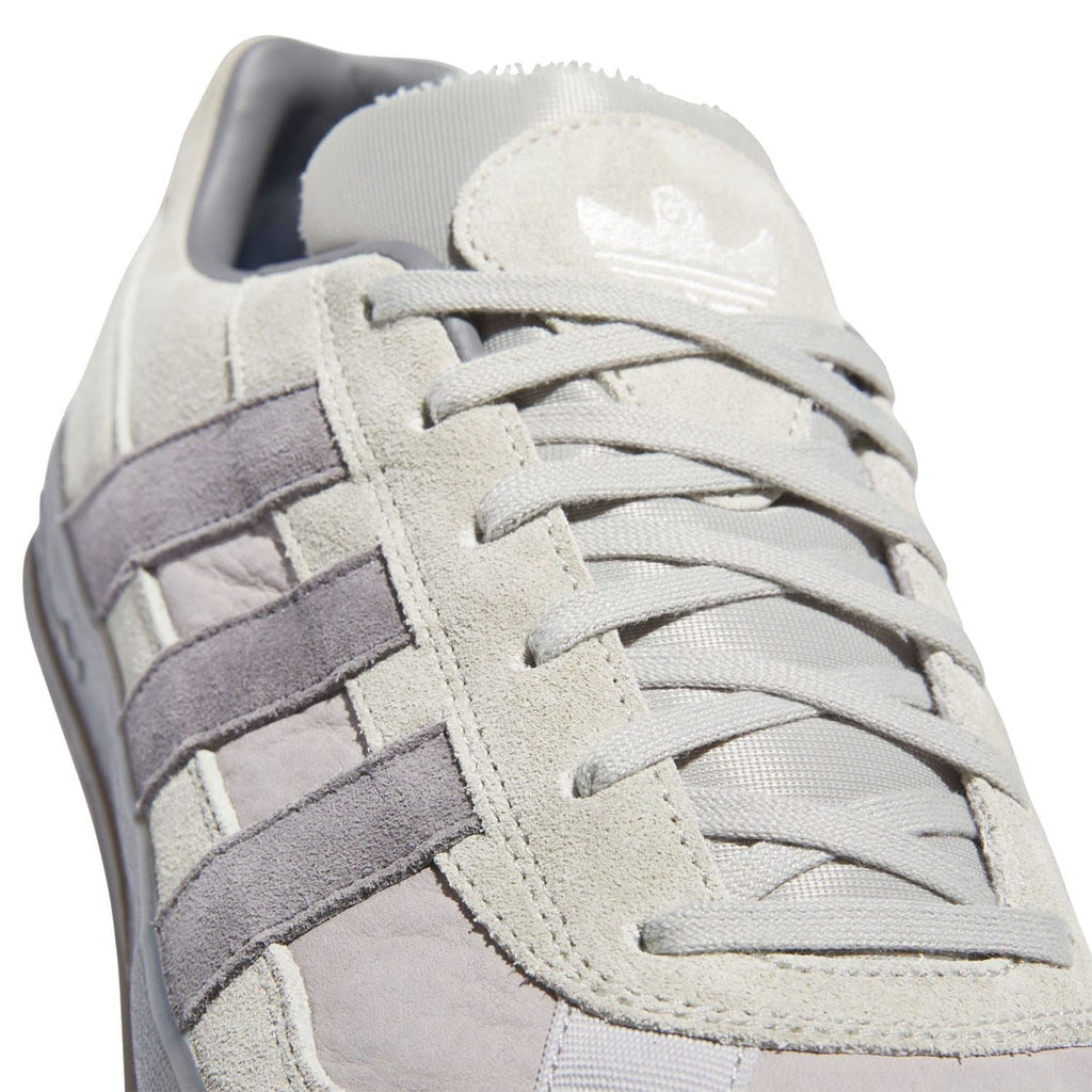 Close-up of beige suede upper with lace-up, purple stripes, and cushioned collar