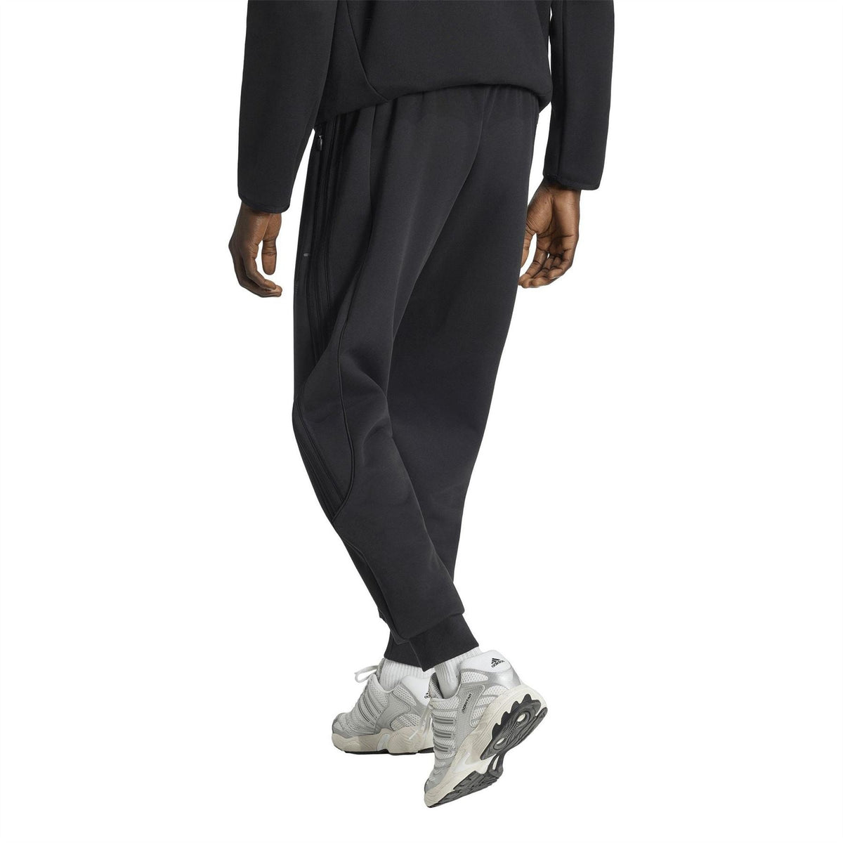 Black track pants with elastic waist, draped fabric folds, ankle cuffs and trefoil logo