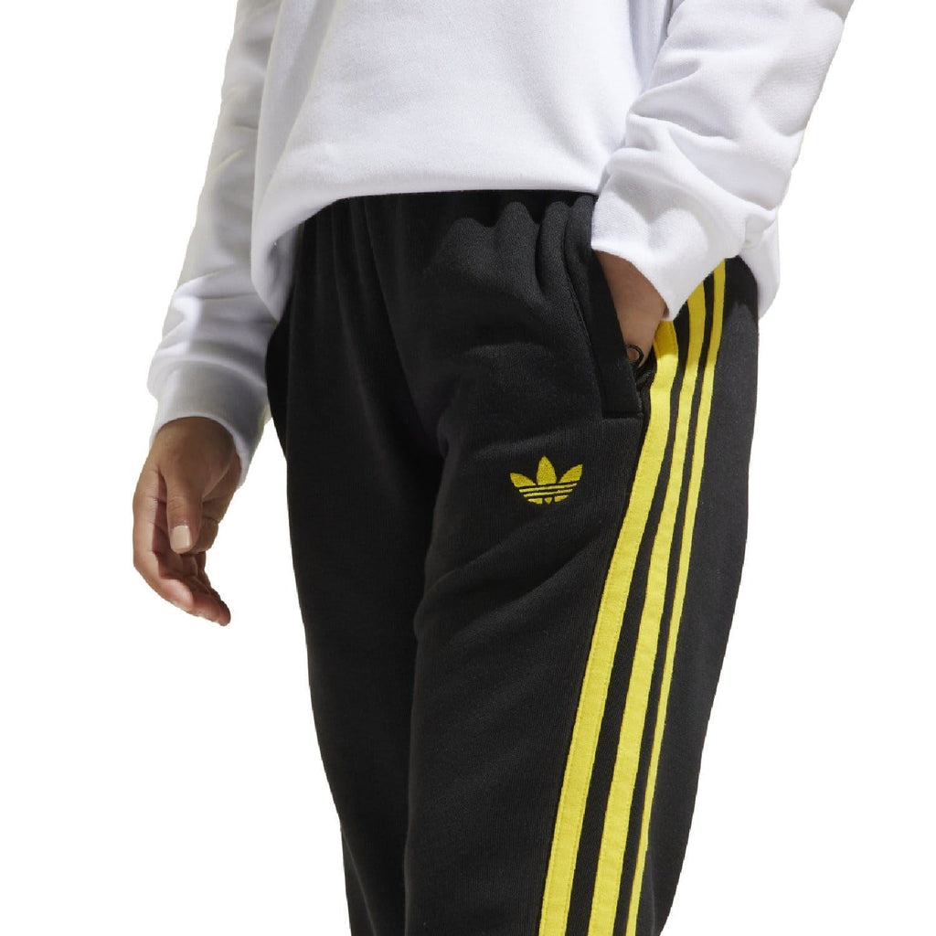 Black kids joggers with yellow side stripes and small yellow adidas trefoil on thigh.