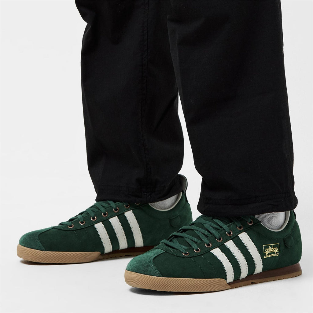 Green Samba low-top sneakers with white stripes, worn with black pants