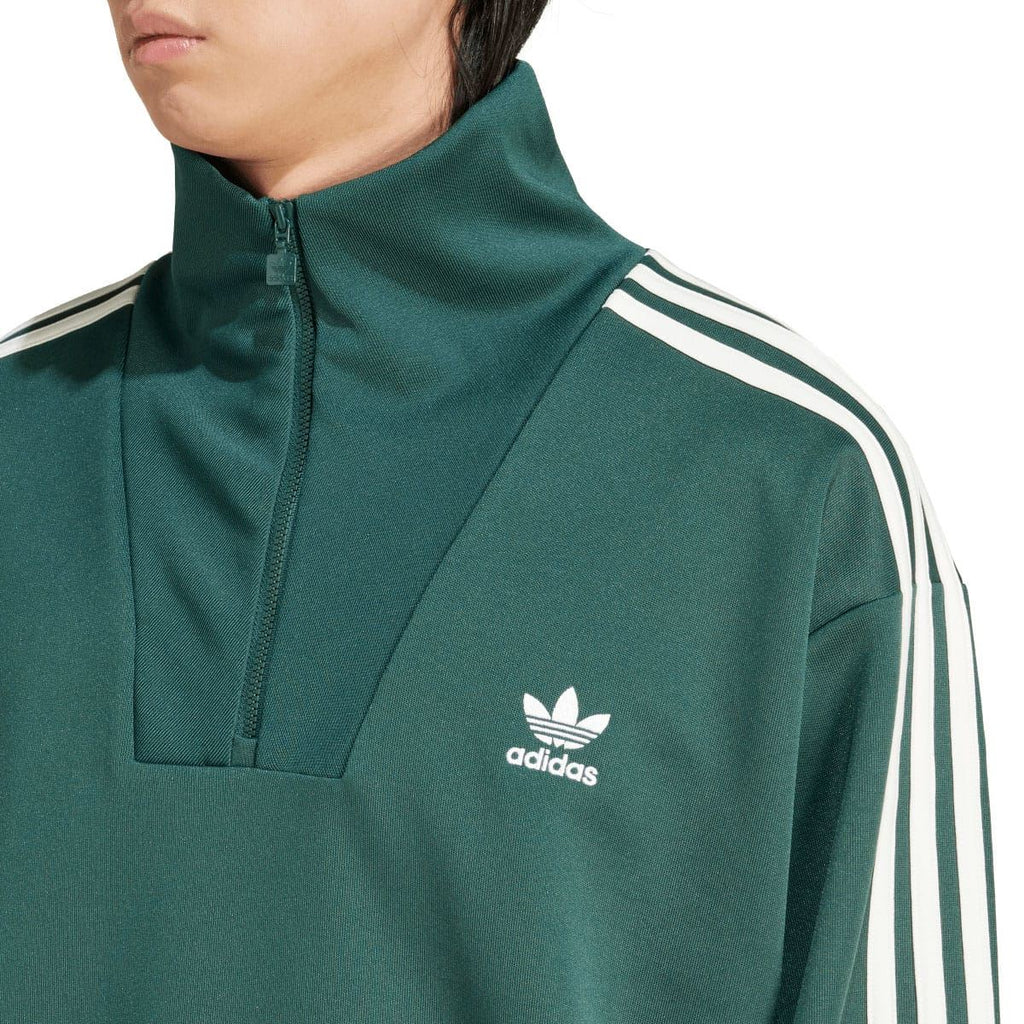 Close-up of green adidas track top: funnel neck quarter-zip and white trefoil logo