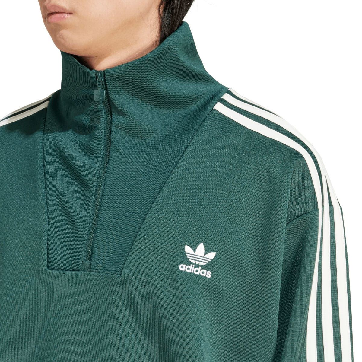 Close-up of green adidas track top: funnel neck quarter-zip and white trefoil logo