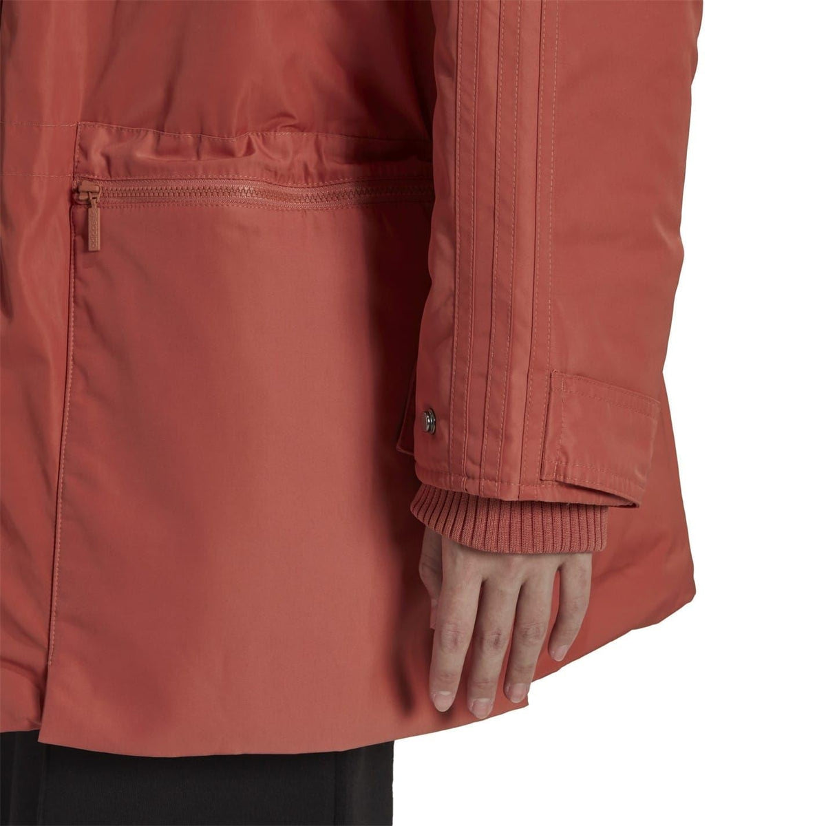 Close-up of burgundy parka front: zip placket, flap pocket, and ribbed cuff.