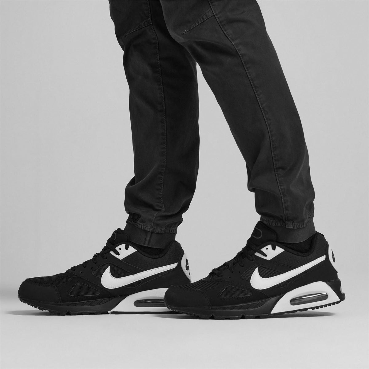 Black trainers worn with dark pants; white swoosh and air unit on midsoles