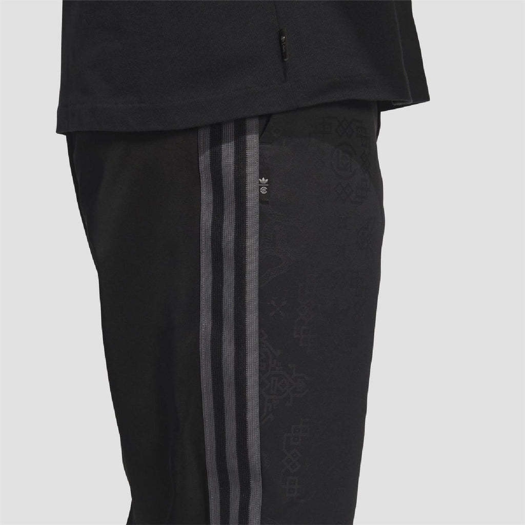 Black track pants close-up: vertical side stripes and textured allover print