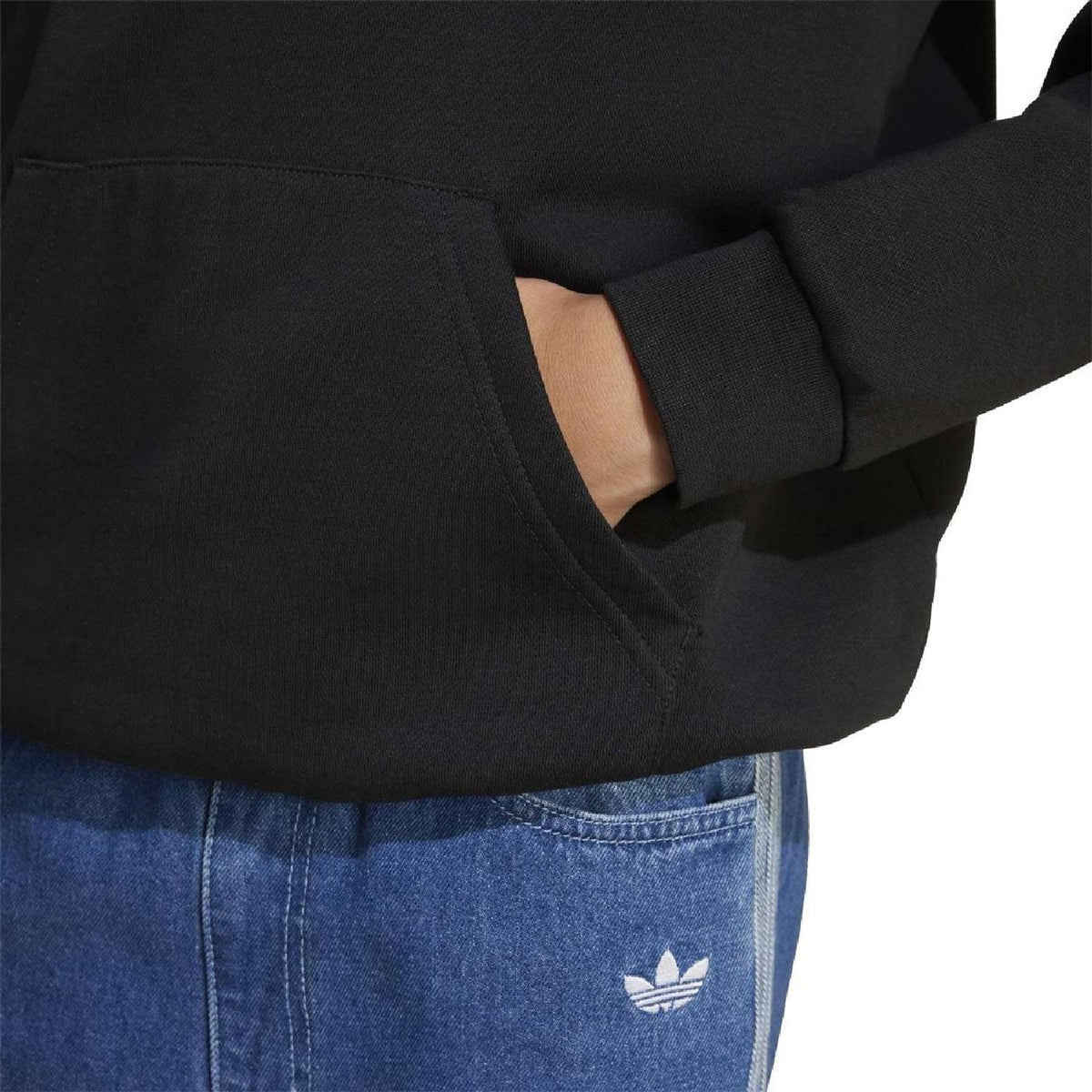 Black sweatshirt sleeve detail with ribbed cuff and adidas patch on kangaroo pocket.