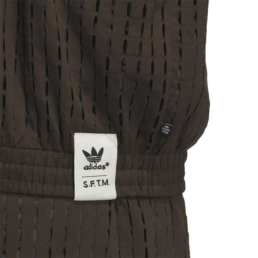 Brown jacket sleeve label area with adidas Trefoil and S.F.T.M. text patch