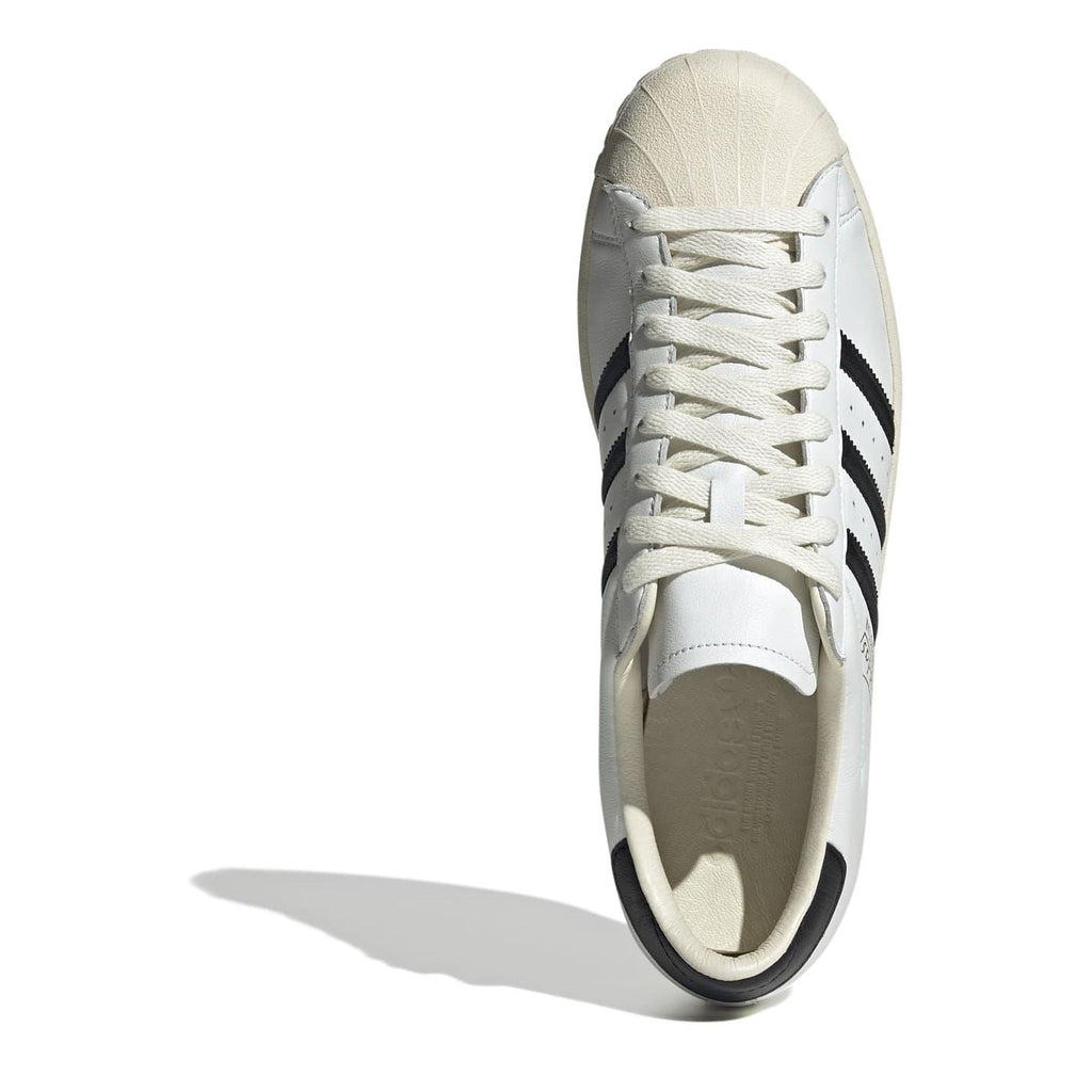 White low-top sneakers with lace-up front and beige sole, side view