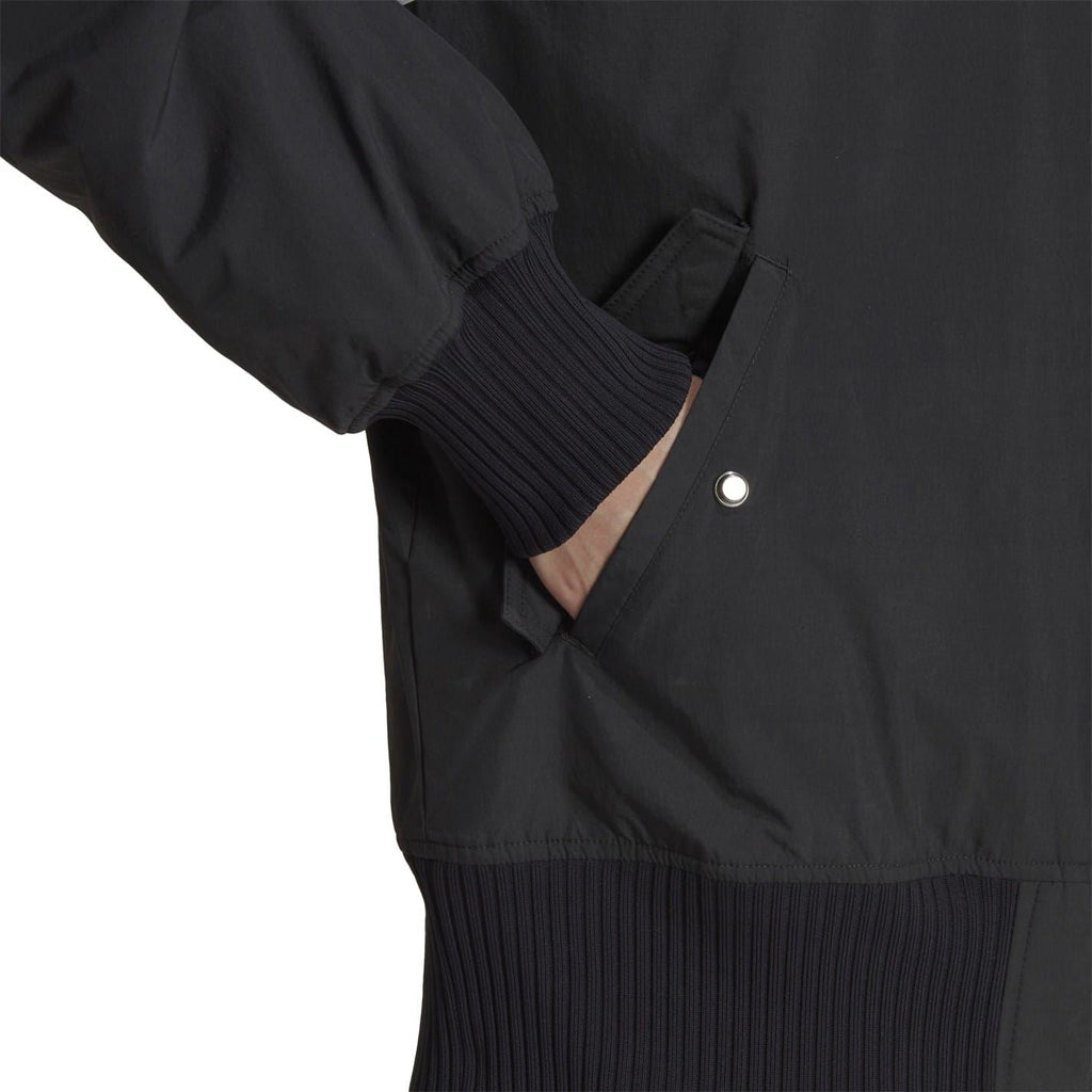 Dark bomber jacket close-up of ribbed cuff and hem with snap button detail.