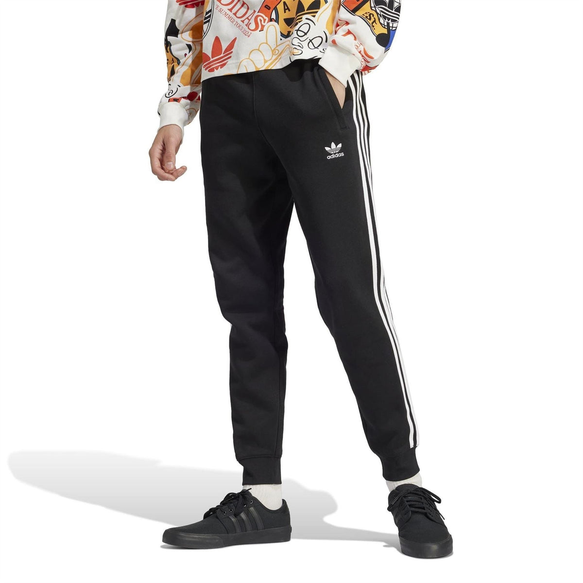 Black slim joggers with white side stripes and ribbed cuffs, worn with sneakers