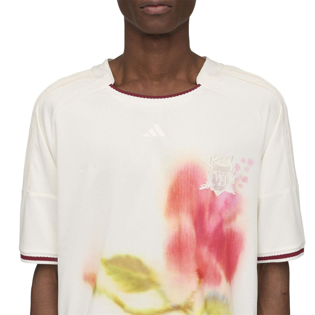 White football jersey close-up with watercolor floral print and small adidas logo on chest