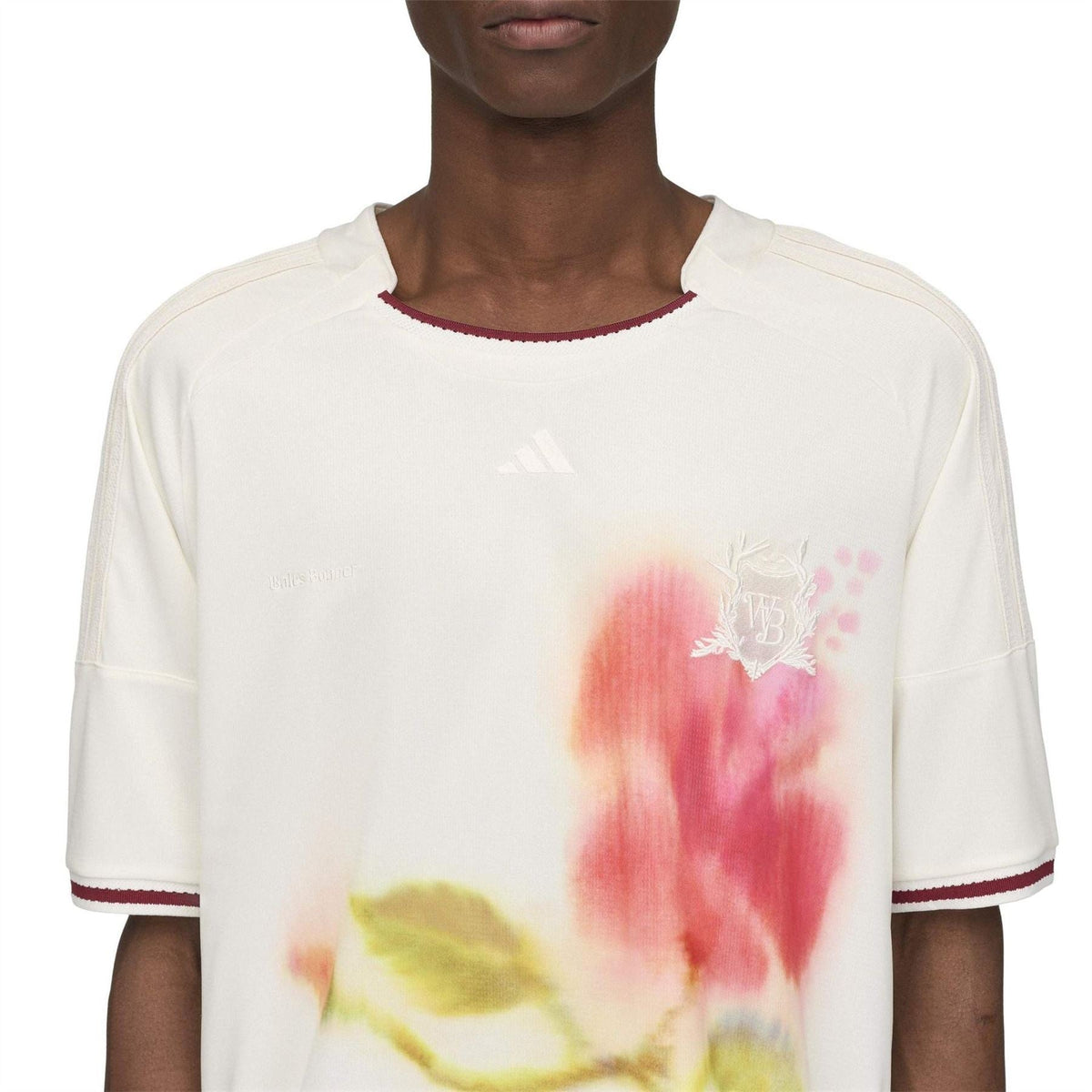 White football jersey close-up with watercolor floral print and small adidas logo on chest