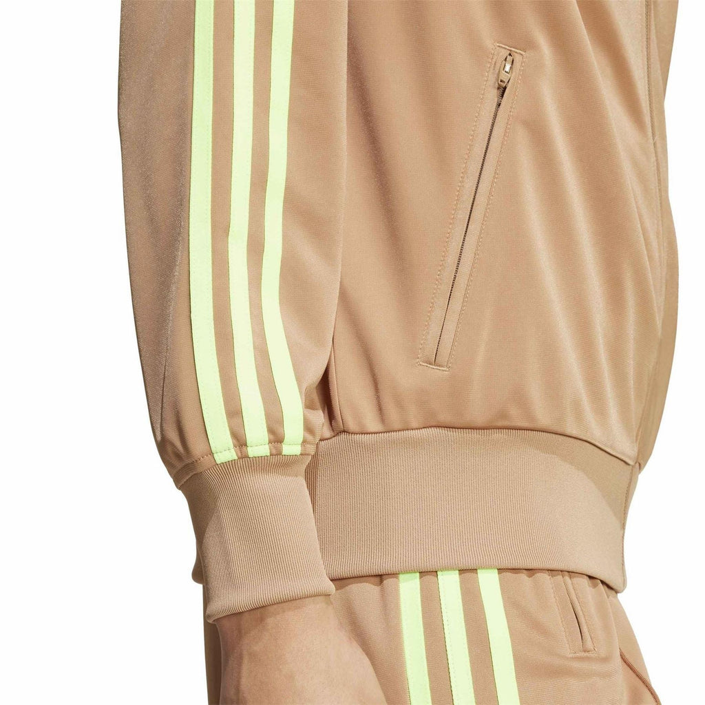 Tan track jacket close-up: front zip, welt pocket, and neon green stripe sleeve detail