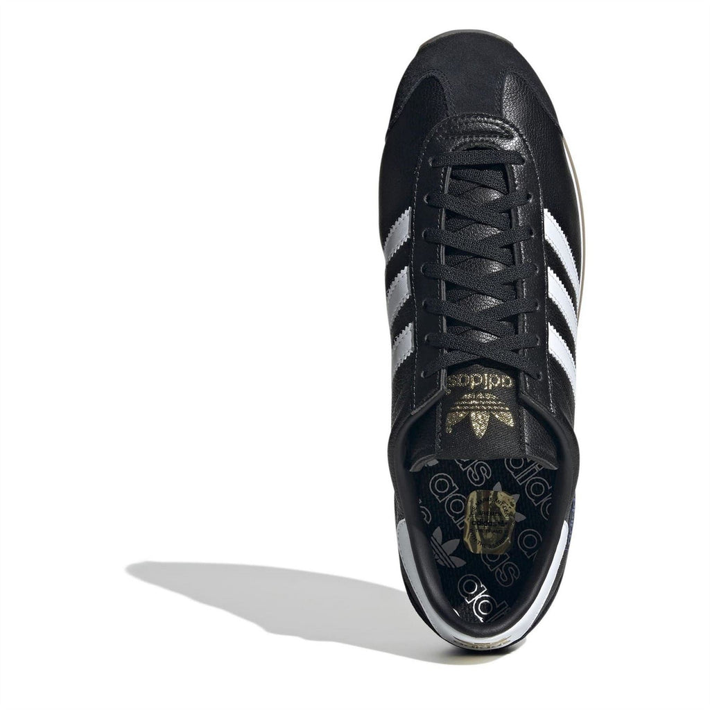 Black lace-up sneakers showing tongue labels, white stripes, and gum sole edge.